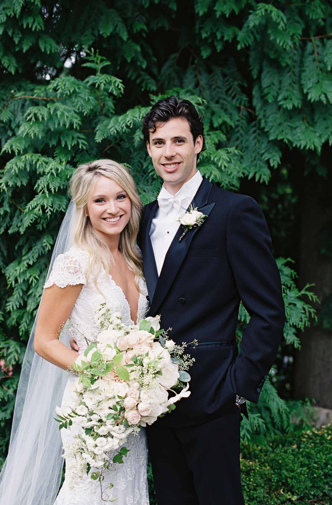 Bride and groom with lush garden style bouquet in blush and cream with greenery