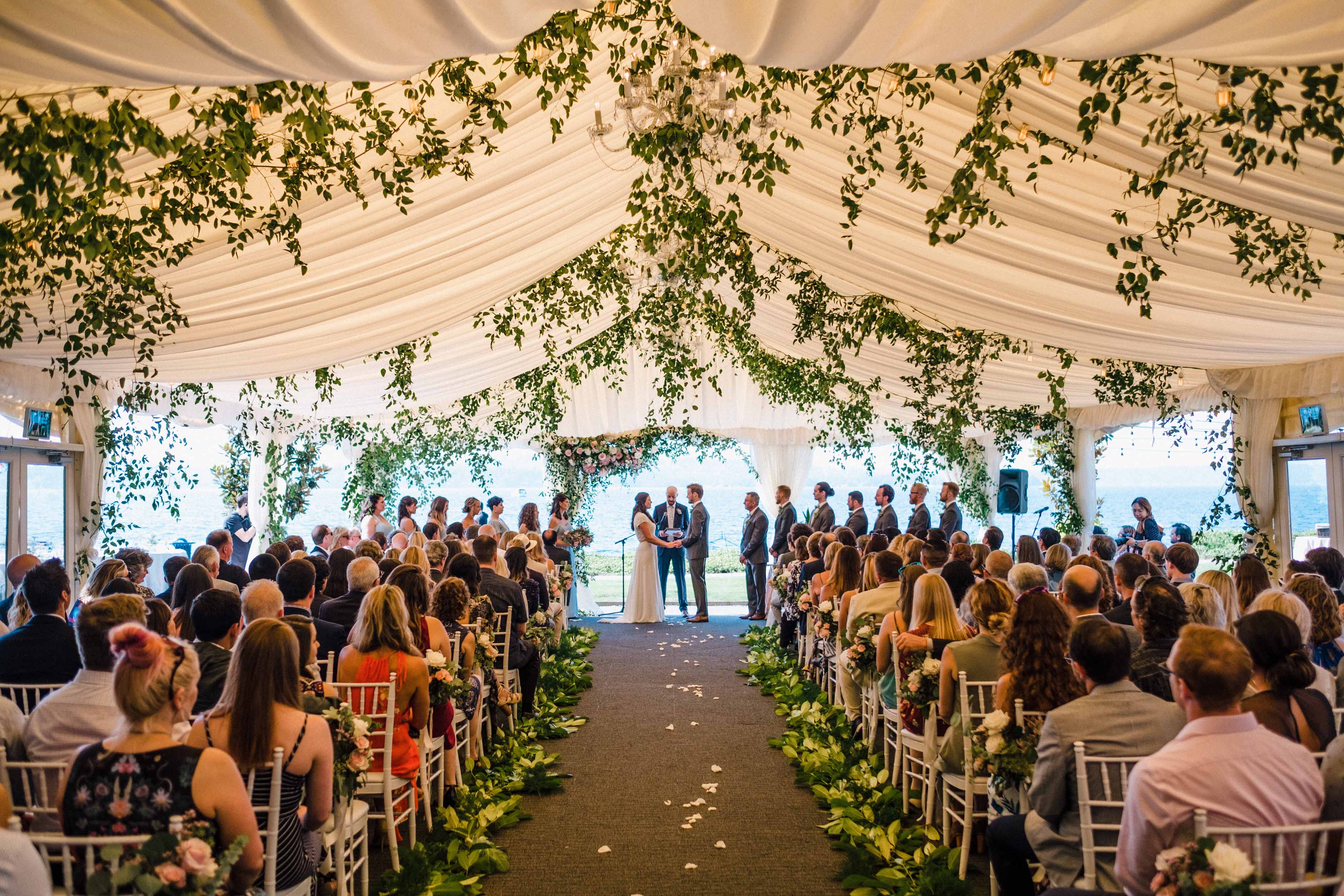 Wedding ceremony with lots of greenery in the tent ceiling at a Woodmark Hotel wedding, Flora Nova Design Seattle