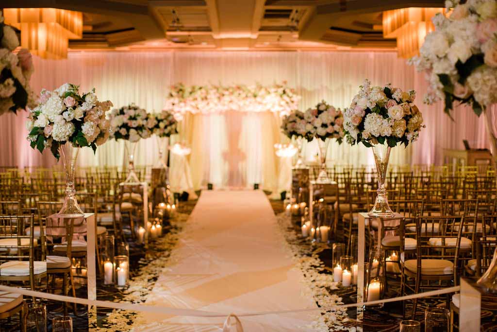 White ceremony aisle with tall arrangements and a white and blush chuppah