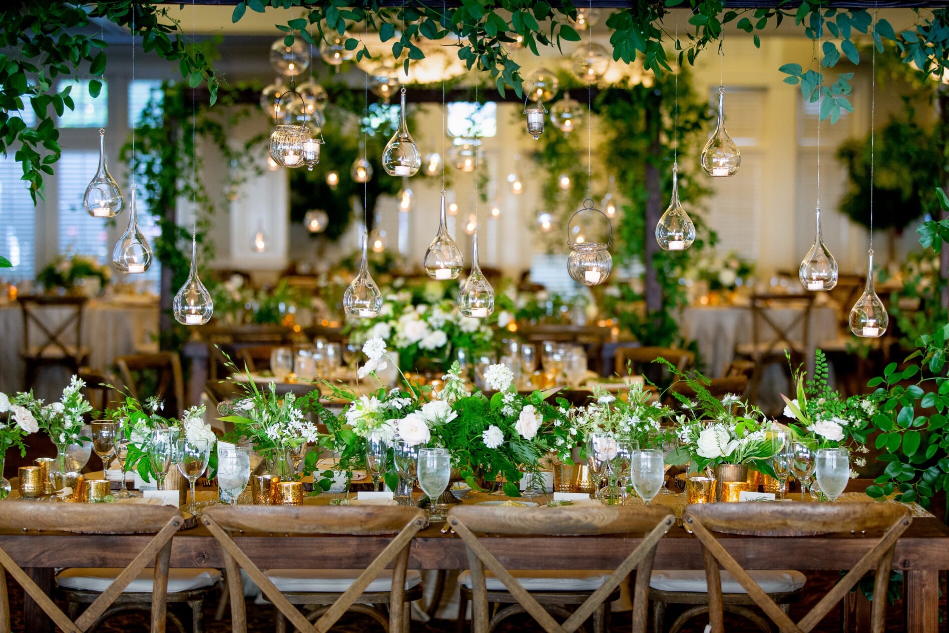 Long wooden table with hanging candles and greenery at this Midsummer Night's Dream Wedding designed by Flora Nova Design