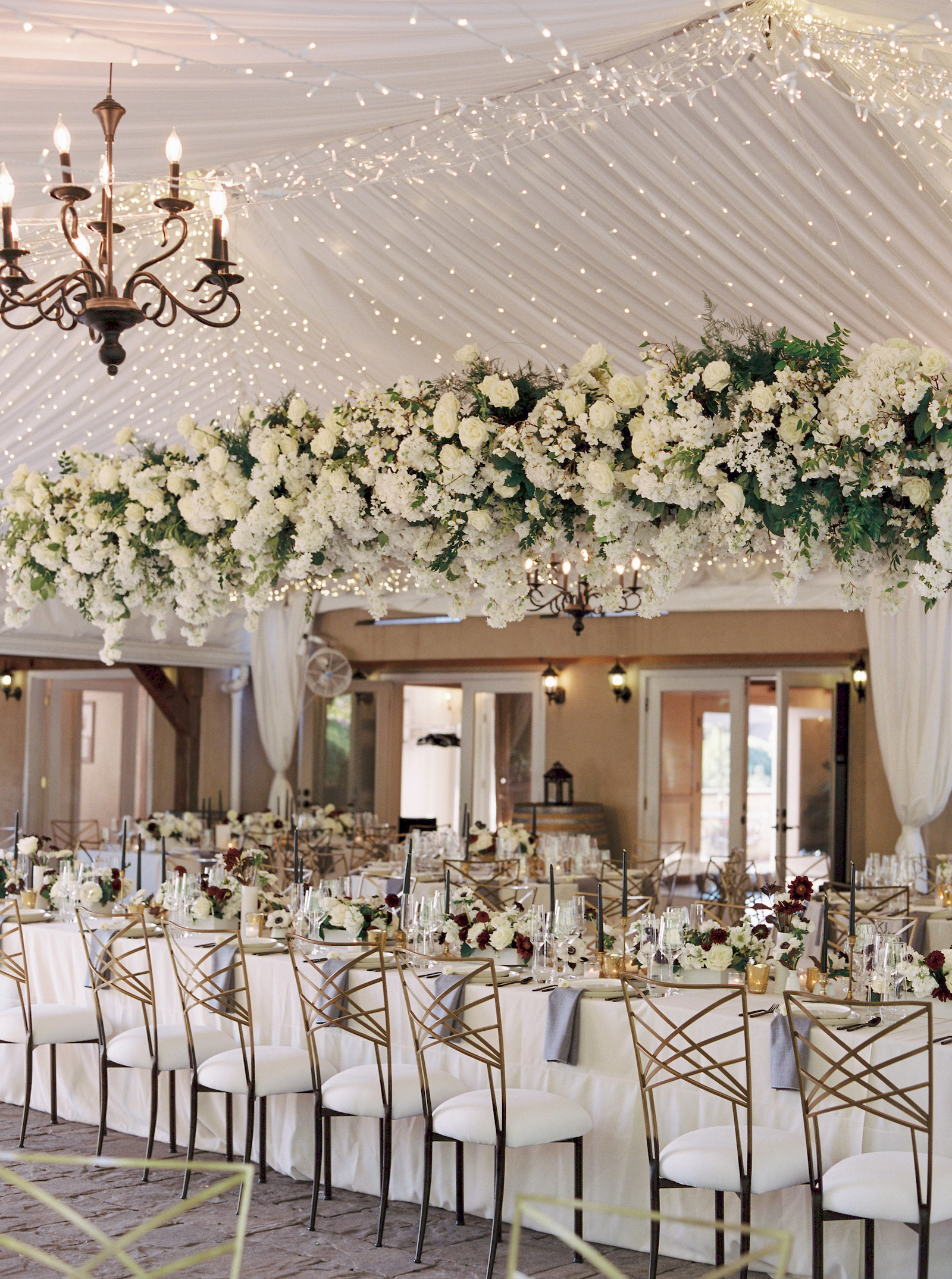 Large floral chandelier above the full length of the head table at Chateau Lill wedding reception