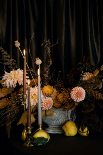 Fall floral centerpiece with peach colored dahlias, brown taper candles, and quince in stone vase, on brown linen - Decorating for the Holidays - Flora Nova Design Seattle