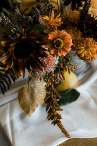 Thanksgiving floral centerpiece with chocolate sunflowers, orange zinnias, dried leaves, yellow chrysanthemums, quince fruit