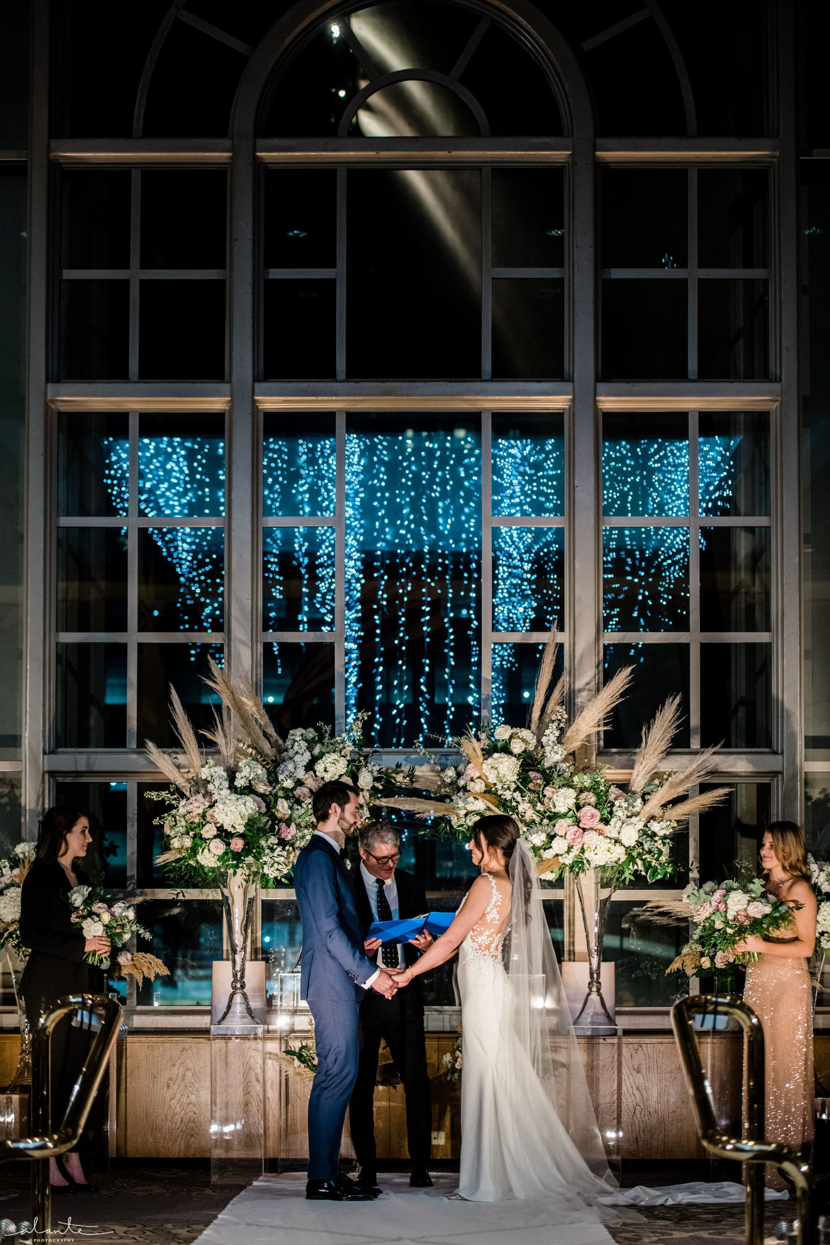 New Years Eve wedding ceremony couple in front of tall white and green floral arrangements with pampas grass.