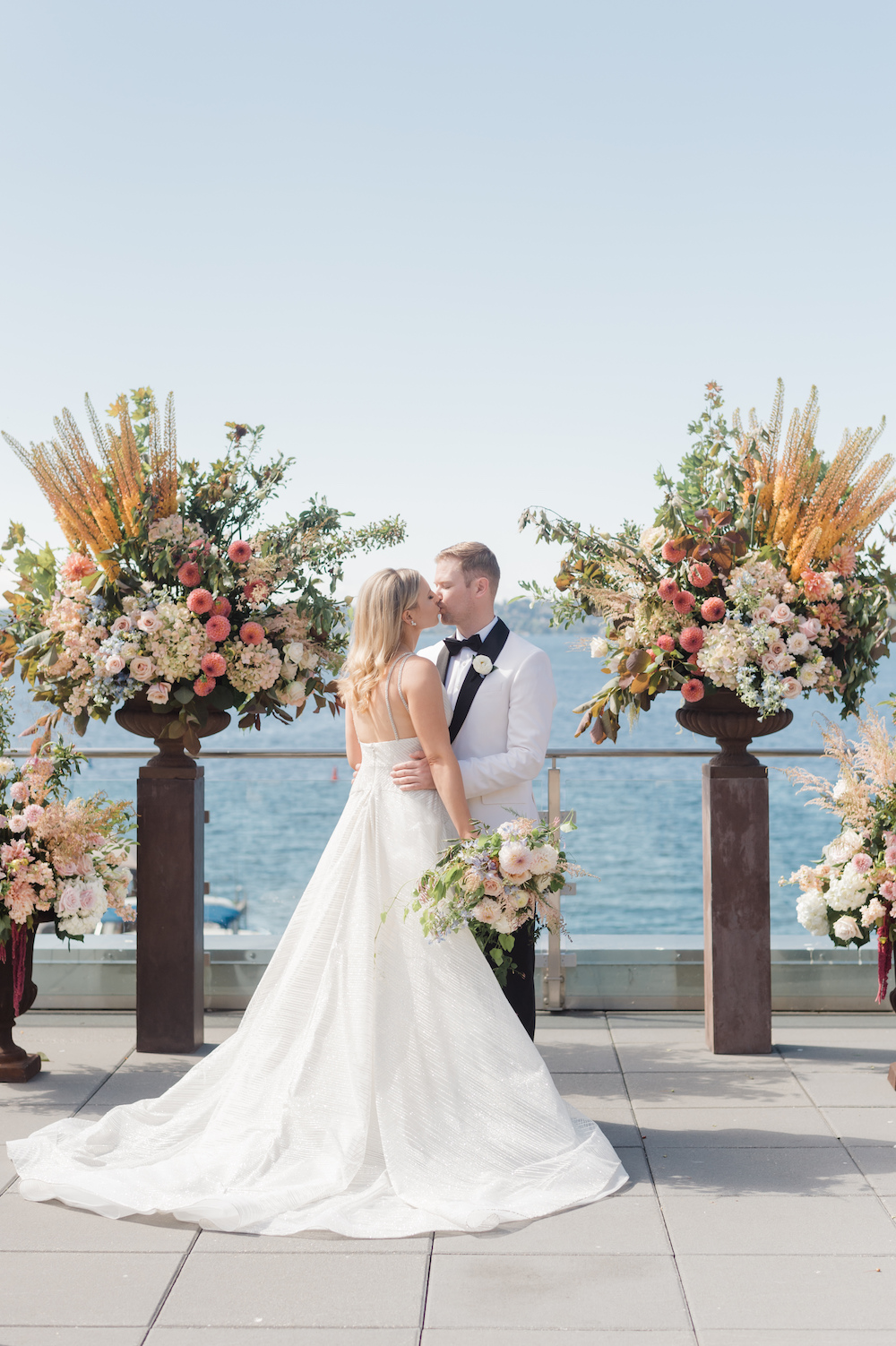 Bride and groom in front of their large floral ceremony backdrop for their Seattle outdoor wedding