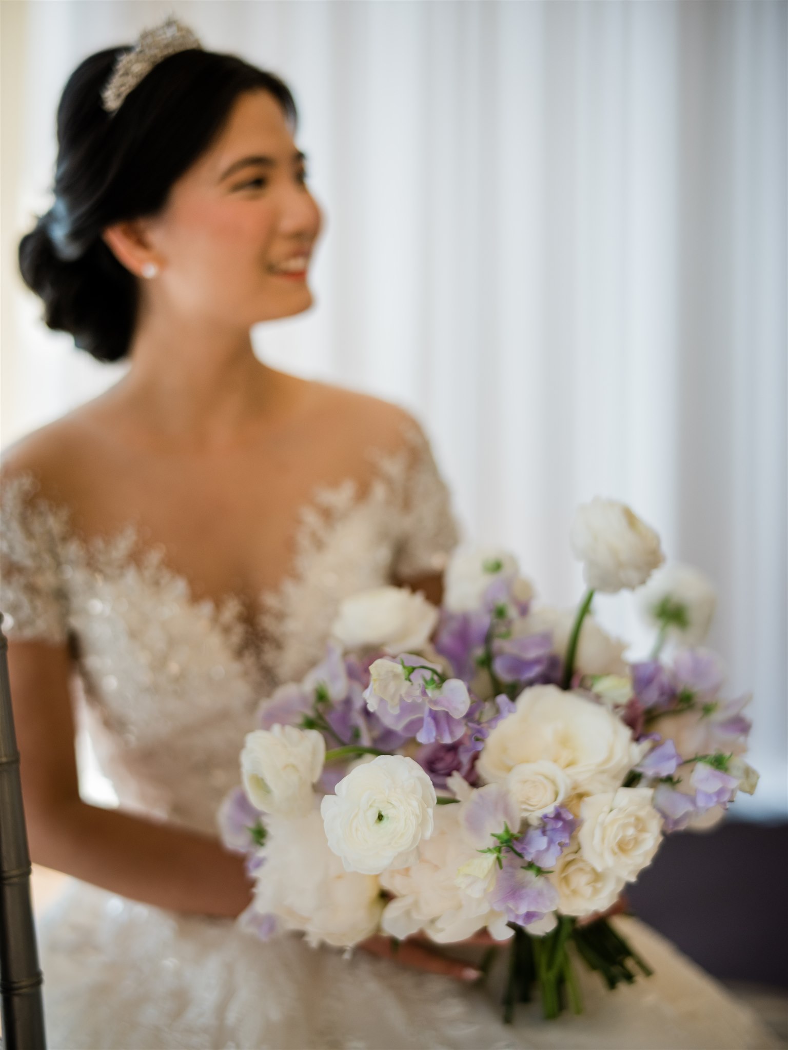Bride holding a bouquet of white peonies, white ranunculus, purple sweet pea