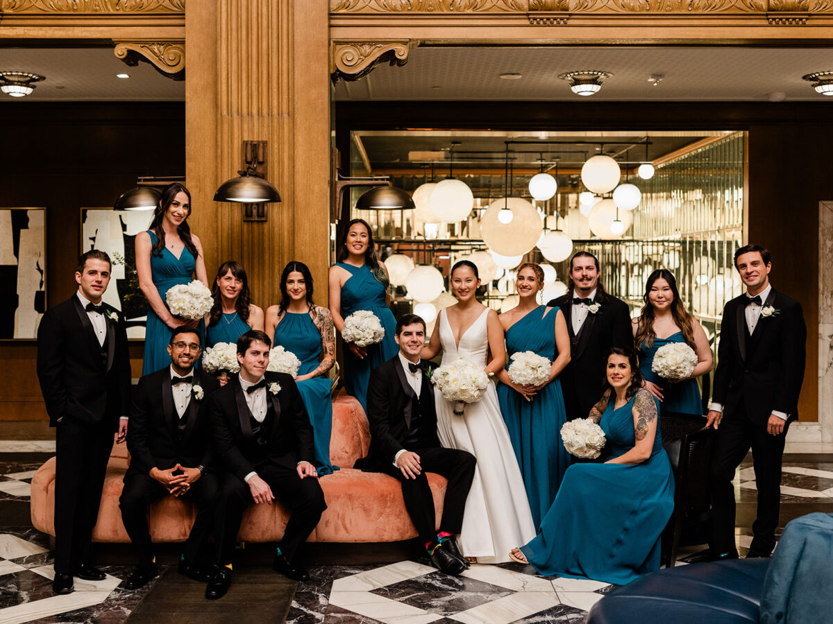 The bridal party and groomsmen stand together in the Fairmont Olympic Hotel with their bouquets and boutonnieres designed by Flora Nova Design.