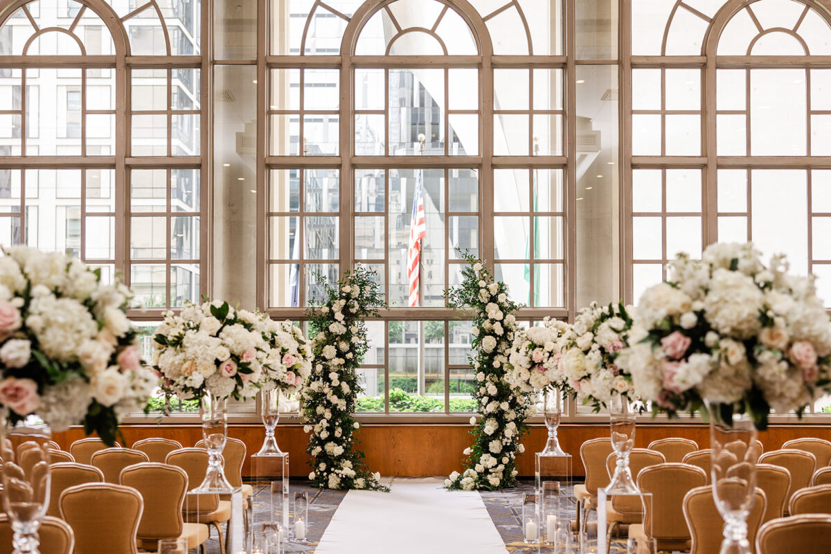 Fairmont Olympic Hotel Garden Room is decorated with tall floral arrangements and candles down the aisle and a lush and charming white and blush arch.