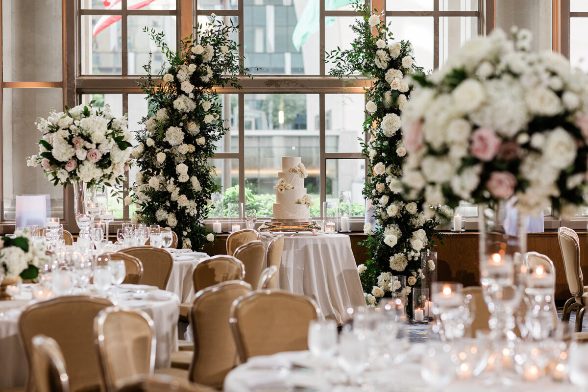 The Garden Room is decorated with tall floral arrangements and the cake table is places under the charming white and blush arch.