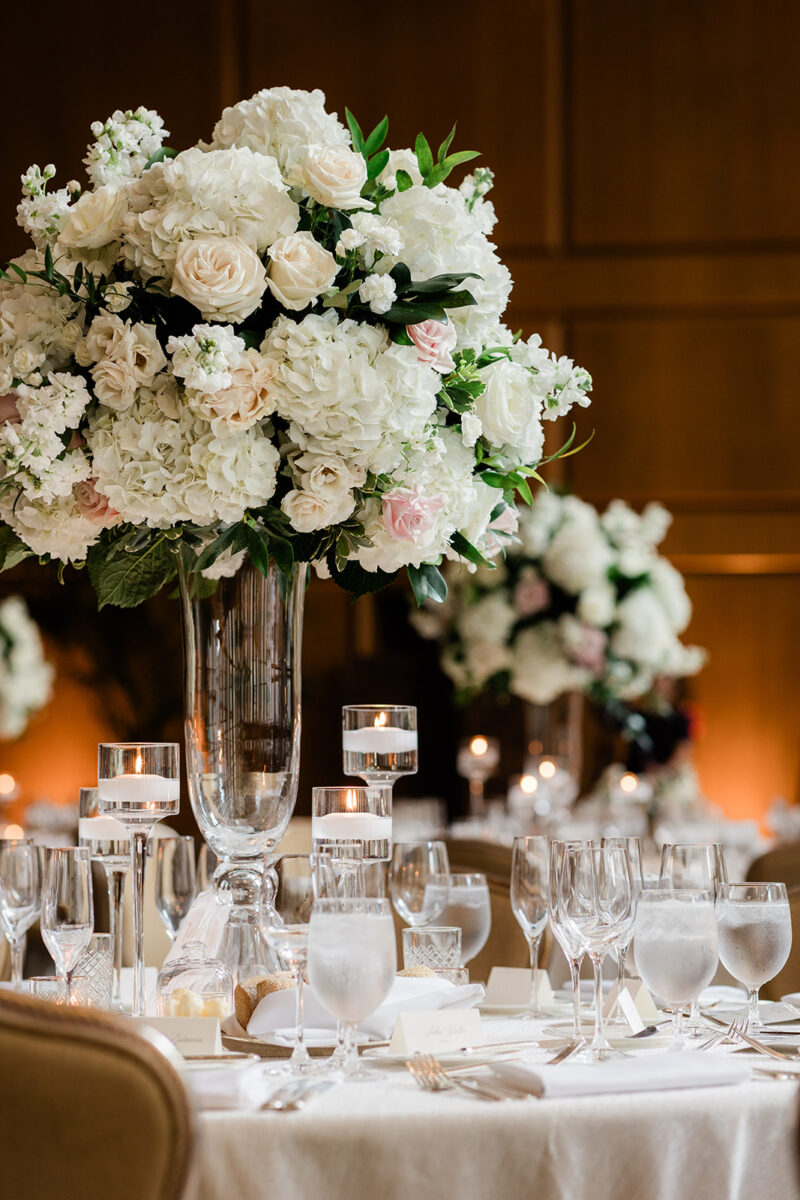 Charming white and blush tall floral arrangement in centerpiece surrounded by floating candles.