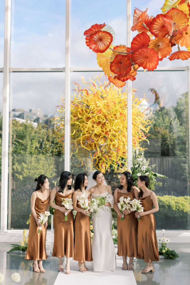 The bride and bridesmaids stand at the front of the aisle and ceremony space at Chihuly.