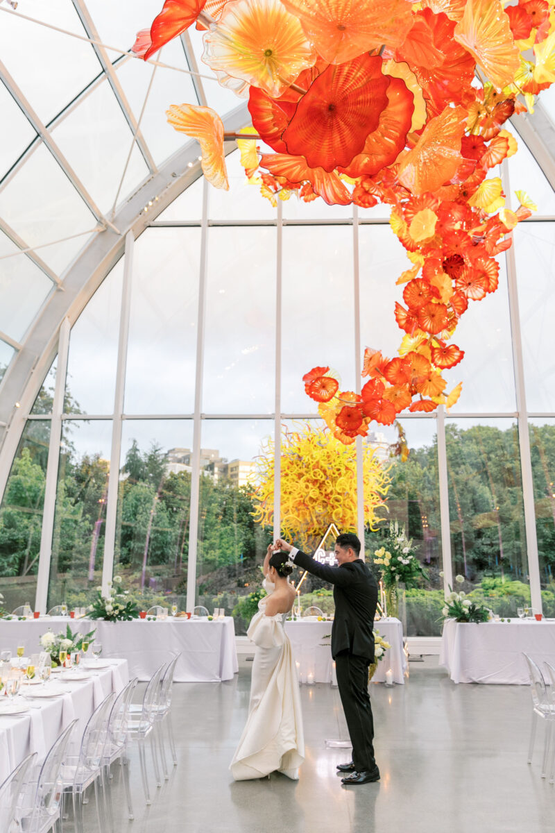 The bride and groom twirl in the decorated Chihuly Glass House.