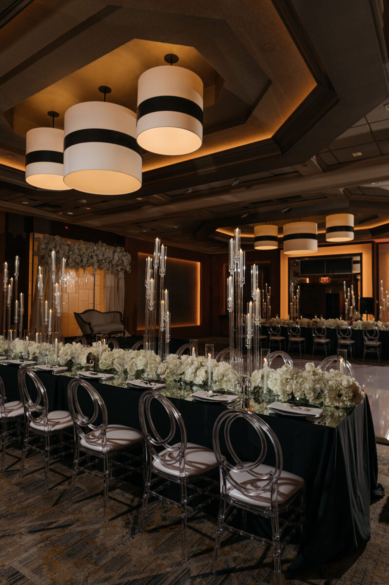 Long head tables lined with fluffy floral arrangements and candelabras in this candlelight wedding At The Bellevue Club Hotel.