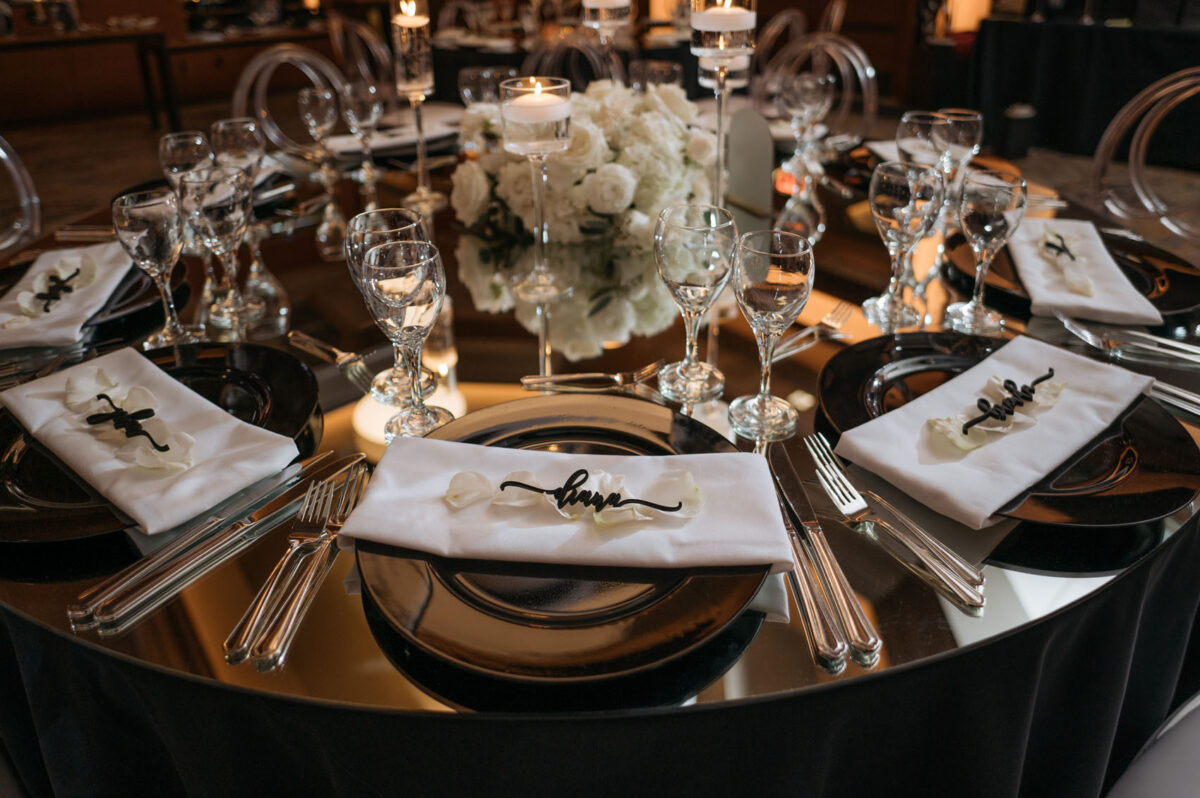 Black place cards lay on white rose petals on each guests charger.