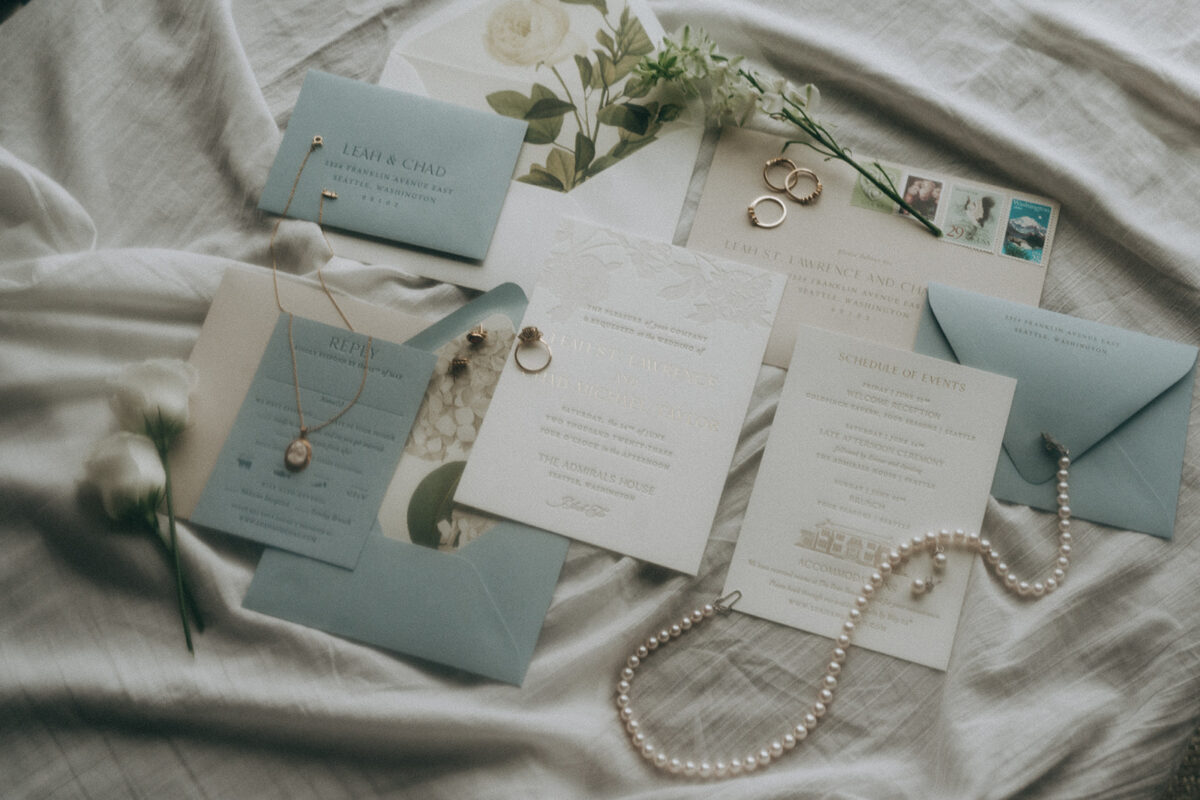 A flat lay with blue and white envelopes accented with jewelry and florals.