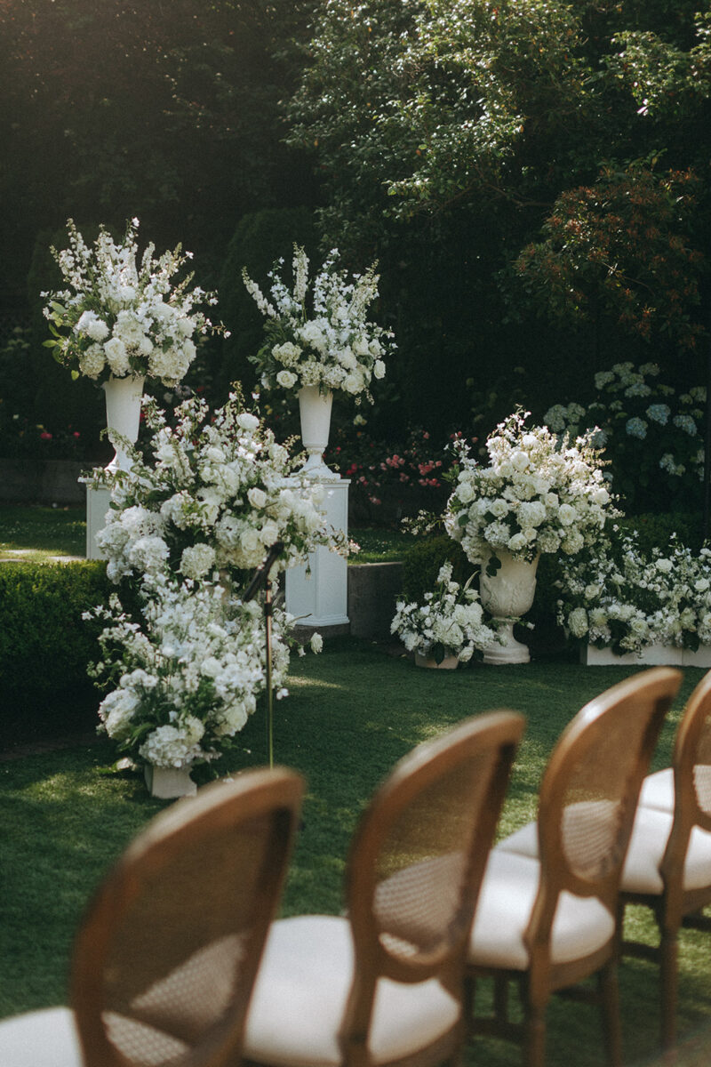 Lush white floral arrangements in urns and planters decorate the from of the ceremony space at The Admiral's House.