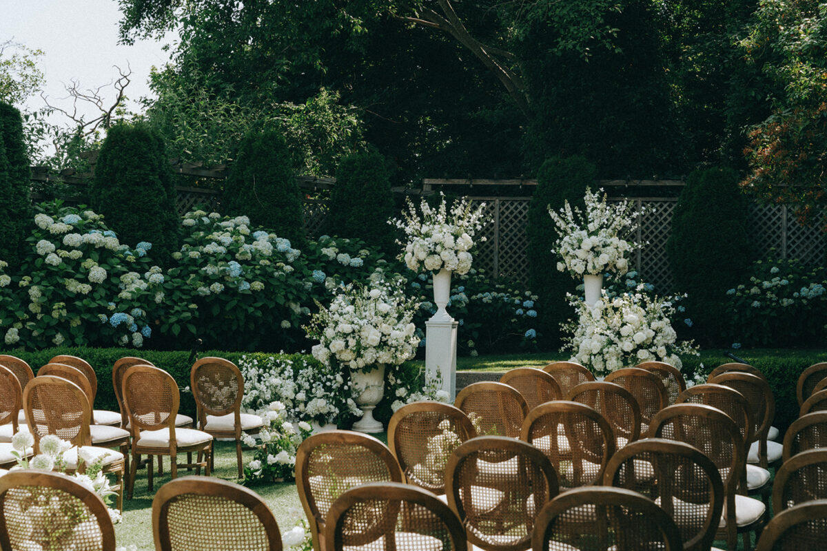 The ceremony is filled with lush white floral arrangements lining the aisle and the front.