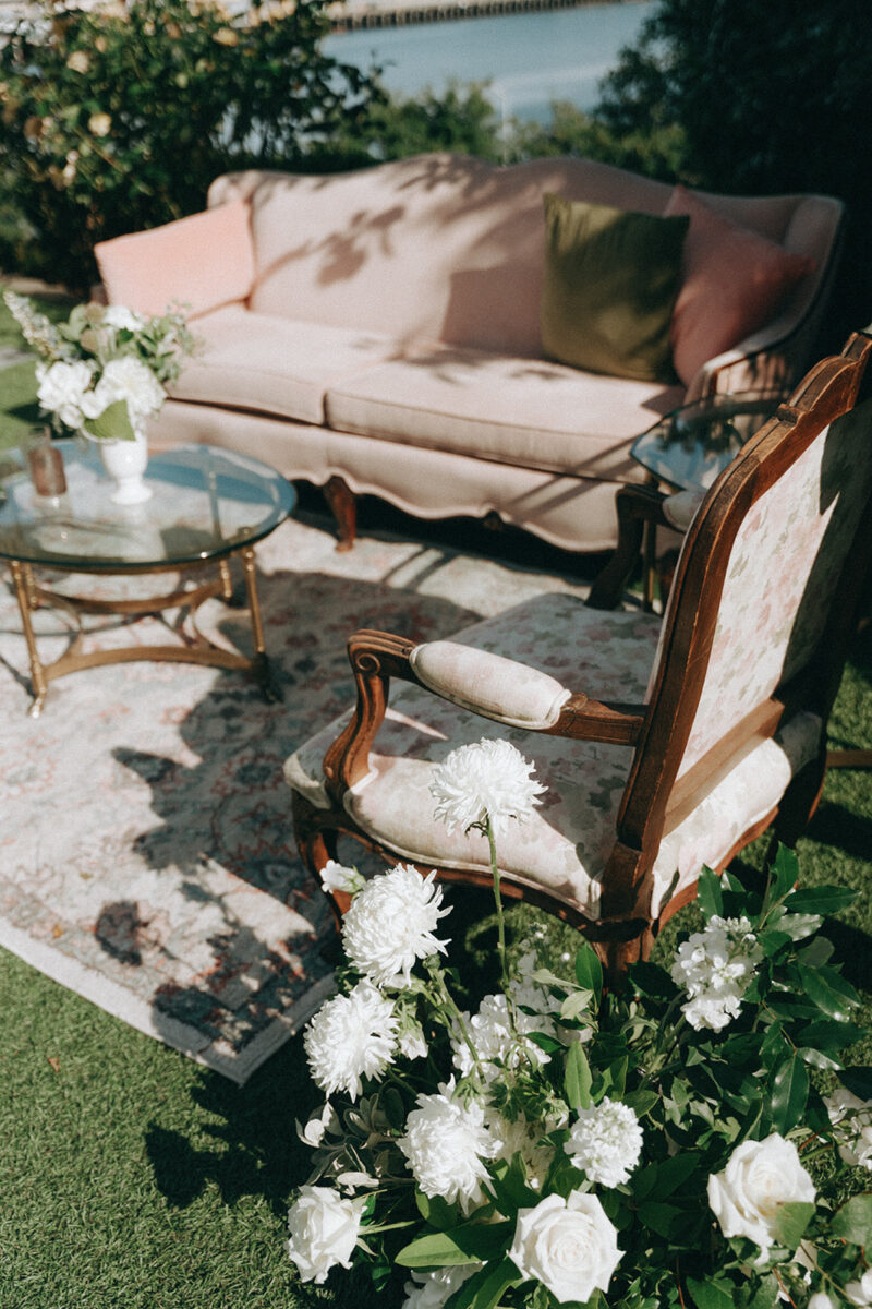 Antique soft seating at The Admiral's House is decorated with florals for guests to socialize in the summer sun