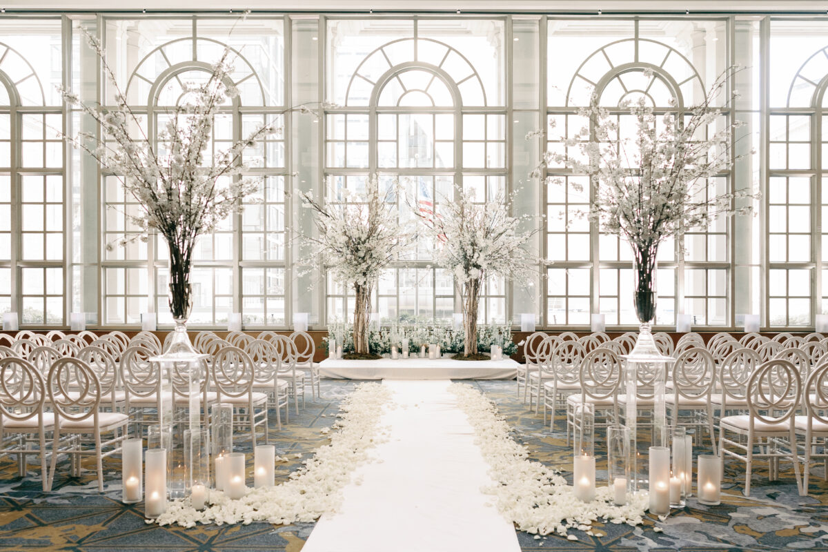 The floor to ceiling windows light up the Garden room at the Fairmont Olympic Hotel for this cherry blossom wedding with cherry blossom trees, candles, and an aisle of petals.