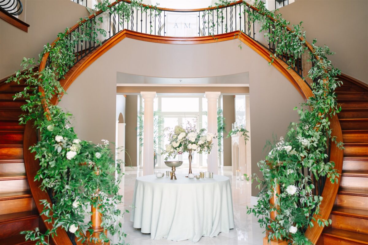 Greenery cascades along both sides of the staircase at the main entrance of the glamorous wedding at a private residence.