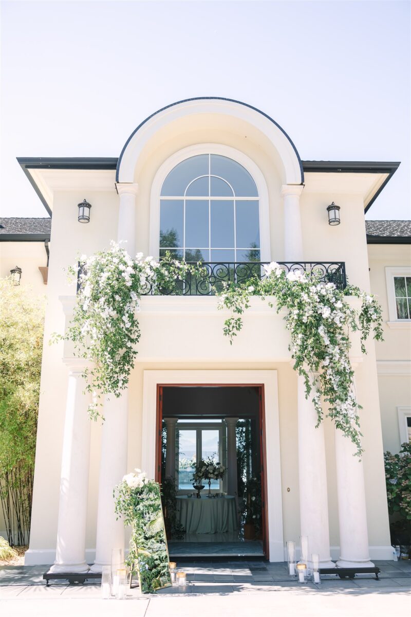 Main entrance of the glamorous wedding at a private residence, decorated with floral cascading vines and candles.