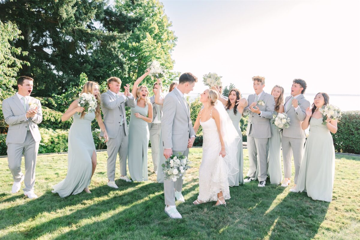 The bride and groom hold hands as the bridal party and groomsmen cheer them on and congratulate them.