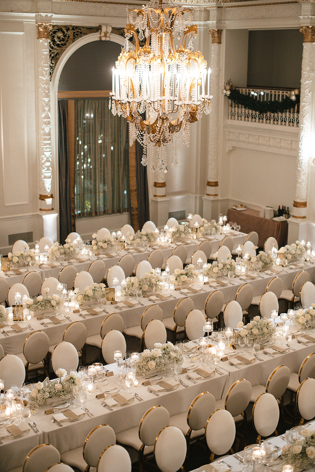 The Spanish Ballroom is filled with tables lined with candles and lush arrangements designed with baby's breath and roses.