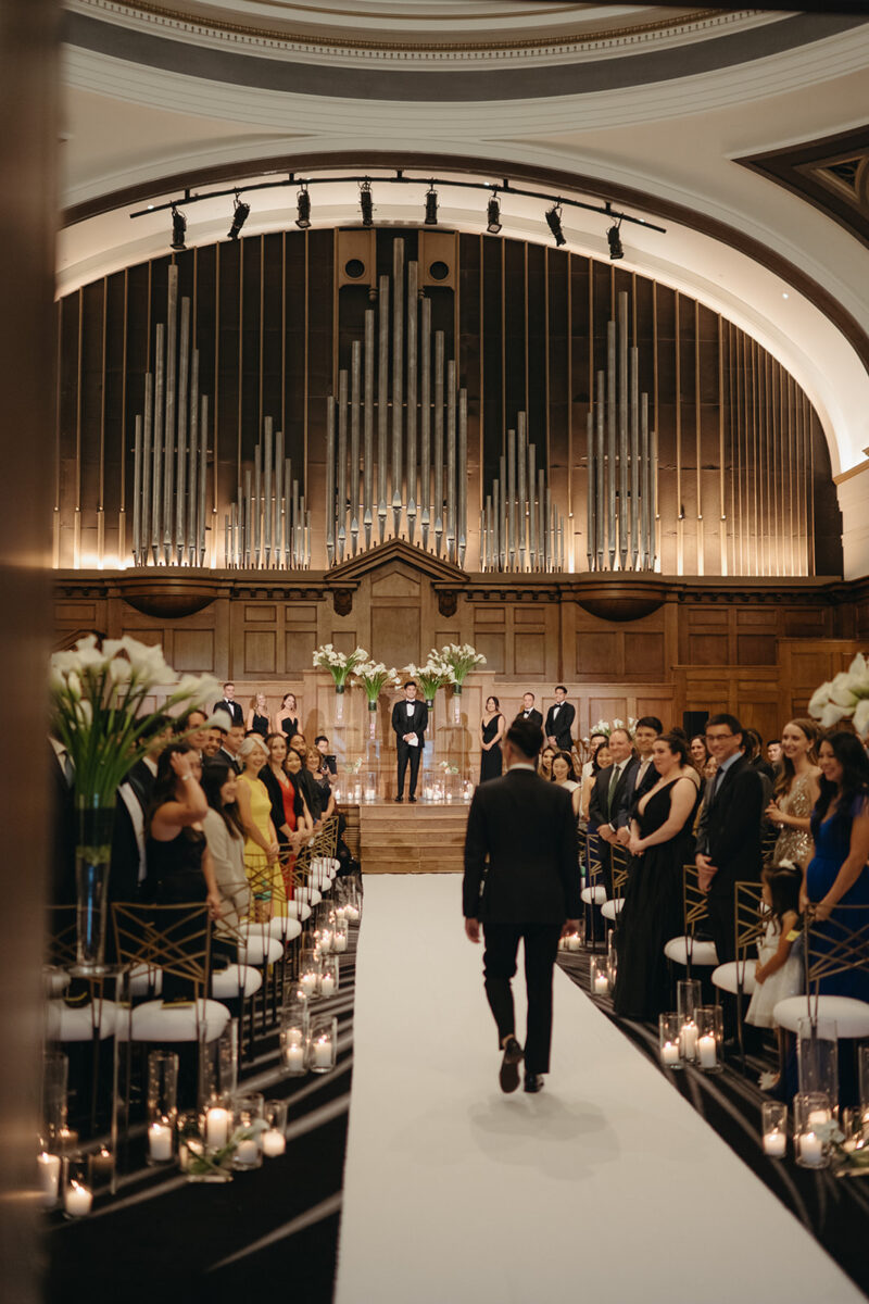 Groom walking down white aisle runner past guests during Elegant Hotel Lotte Wedding ceremony