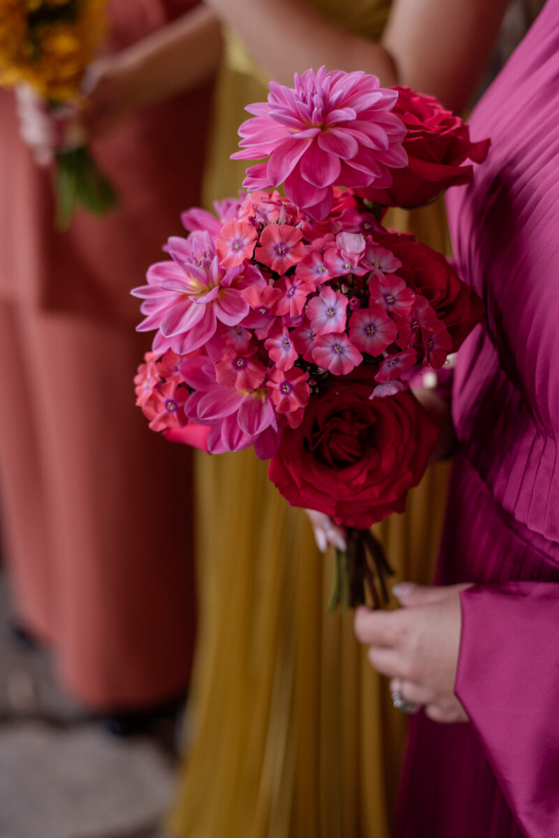 A deep pink bridesmaid bouquet with dahlias, phlox and hot pink roses that matches the bridesmaid's dress.