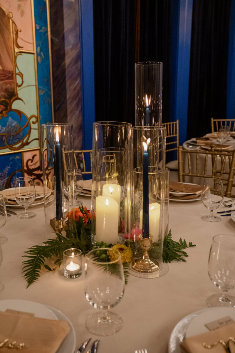 Romantic candlelight centerpiece surrounded by ferns, greenery and finished with three taper candles.